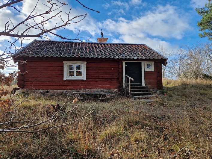 Löktorpet 2024. Liten röd stuga i ett plan.
